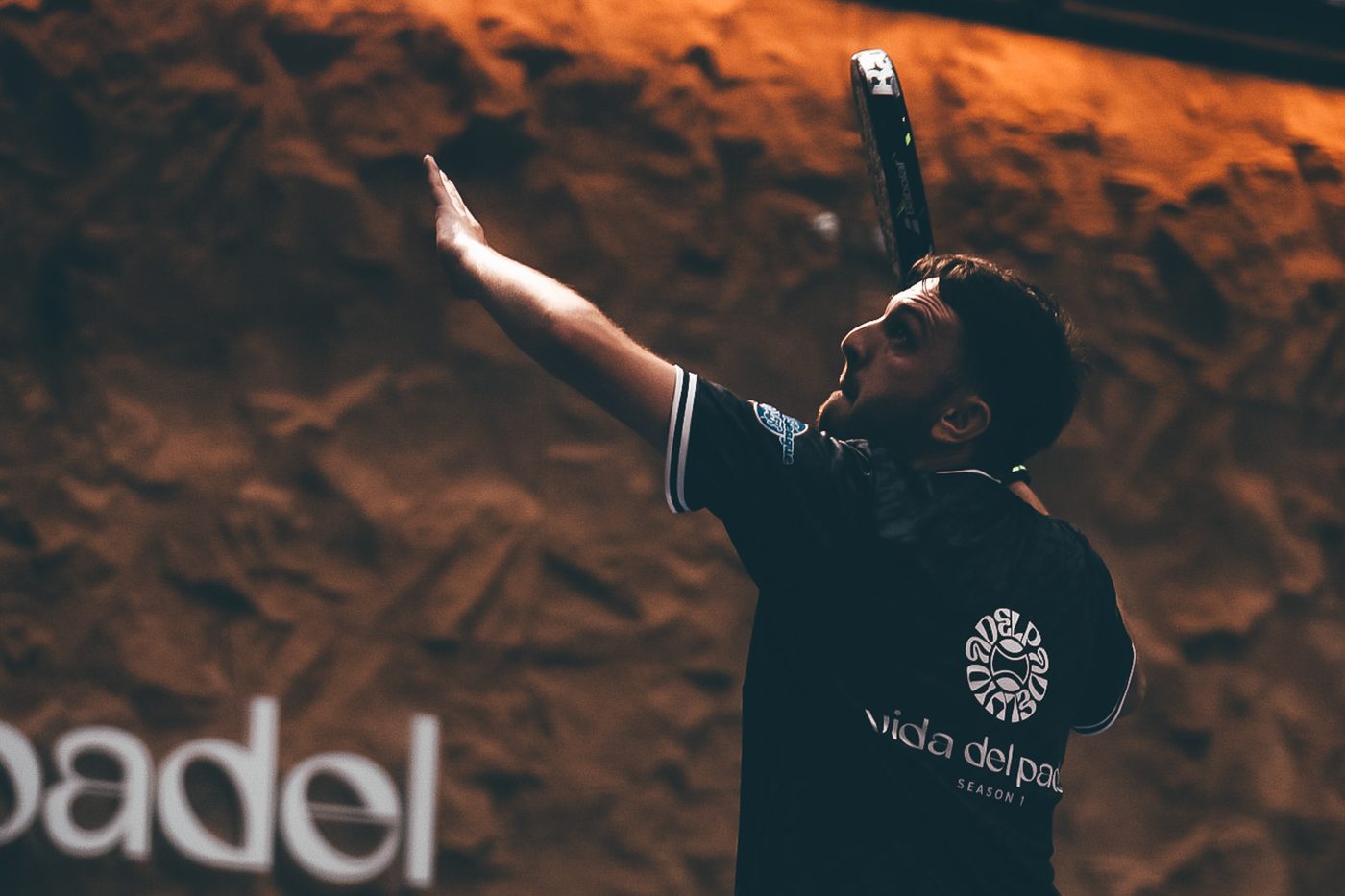 Player serving in a Vida Del Padel shirt